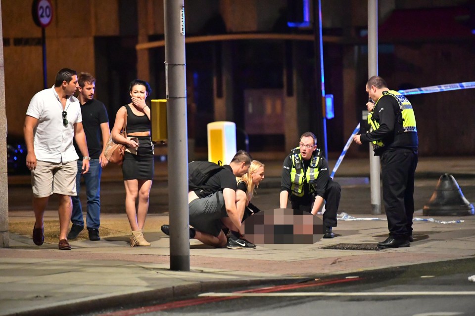 Officers are pictured treating a woman believed to have suffered a fit in London Bridge