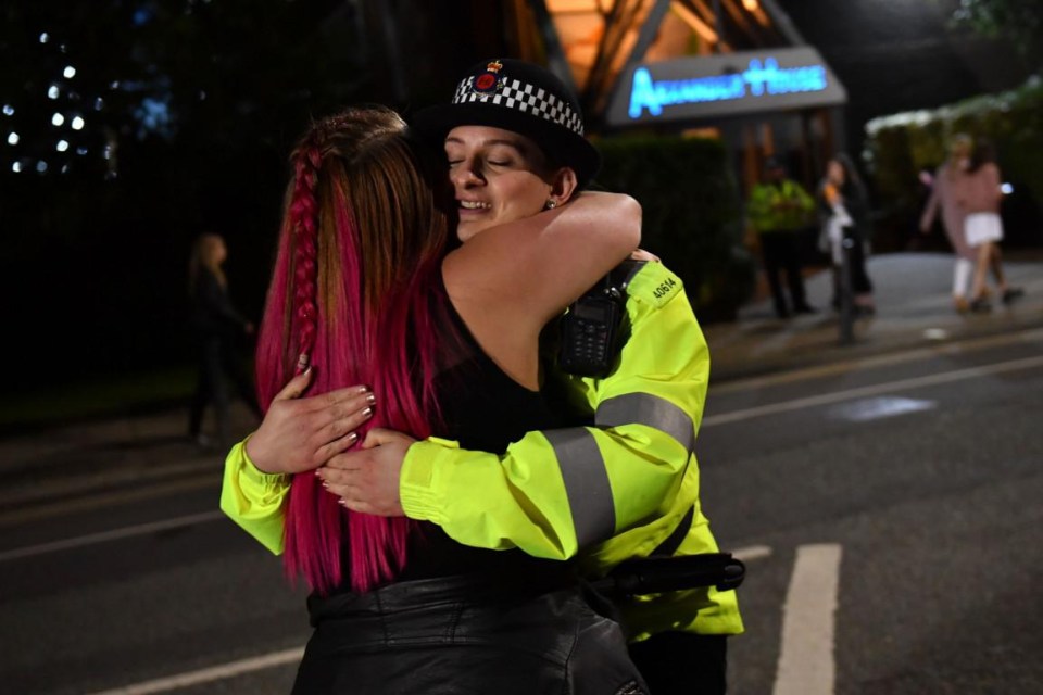 A female police officer hugs another concertgoer