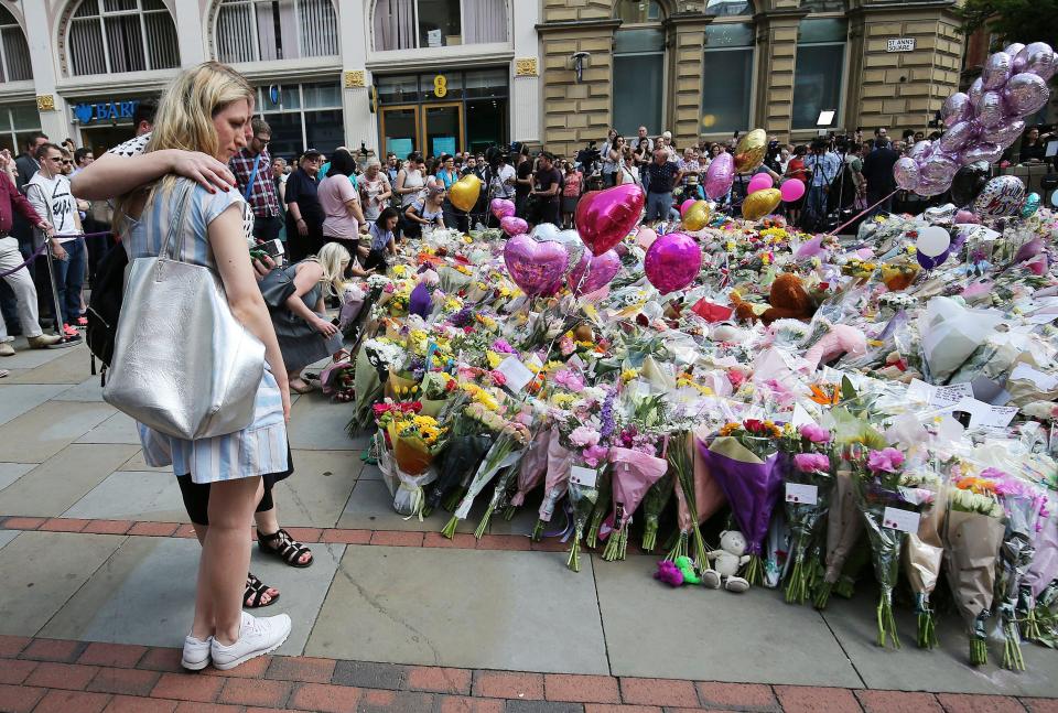  People pay their respects and lay flowers at a memorial for the victims of the Manchester bombing at St Ann's Square, near Manchester Arena