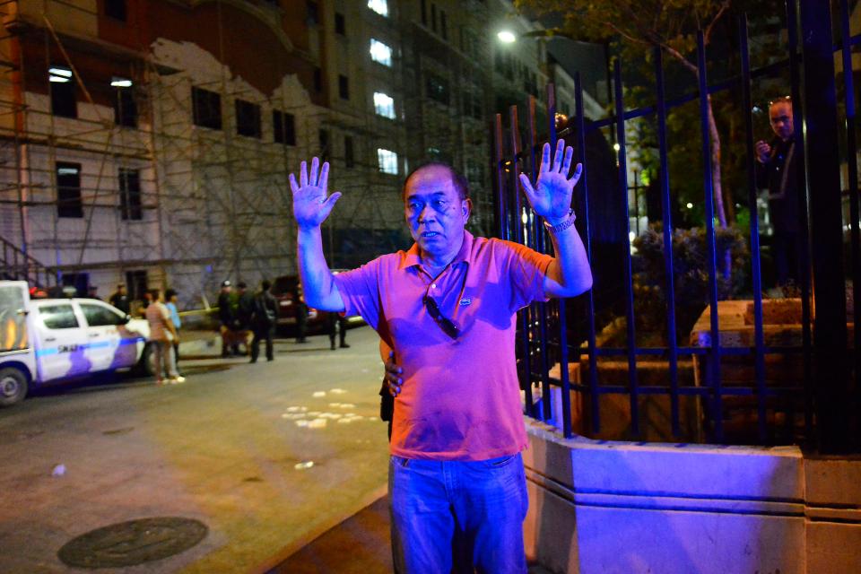  A Filipino man is pictured raising his hands to police outside the Resort World Manila hotel in Pasay city