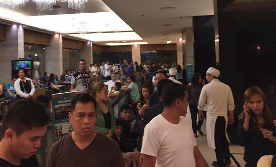  People stand inside the Resorts World Manila complex after explosions rang out