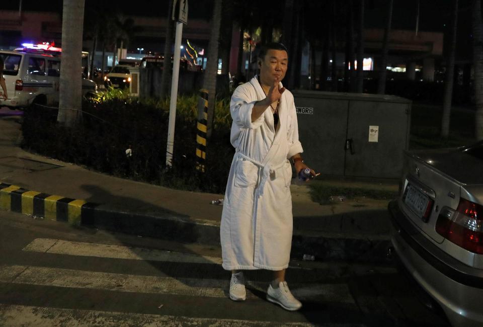  A tourist wearing a bathrobe stands outside after the building was evacuated