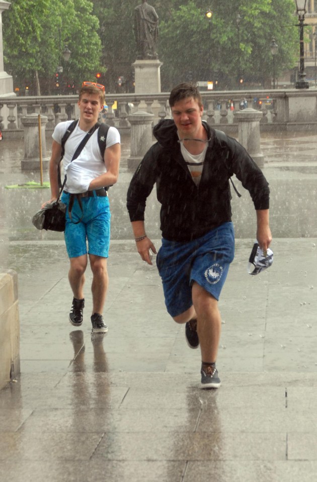 Two men make a dash for cover this afternoon in Trafalgar Square