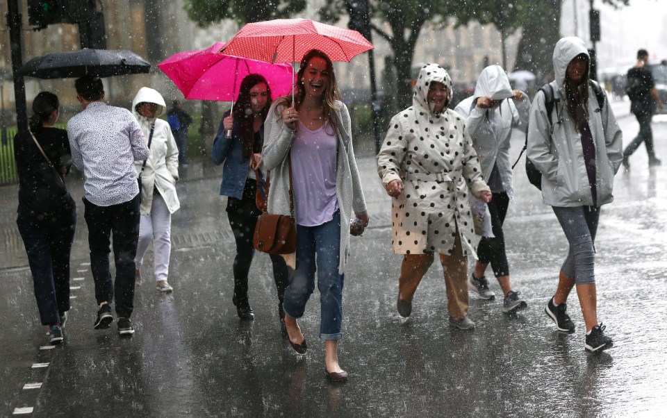 Some found the humour in the flash flooding … one Londoner was snapped mid-laughter as she crossed the street with her umbrella