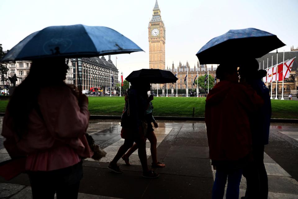  People shelter under umbrellas during afternoon rain showers in Westminster