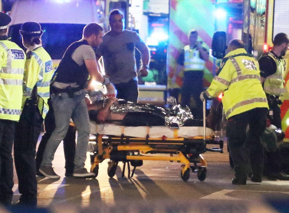 Armed police help a victim who is being stretchered into an ambulance