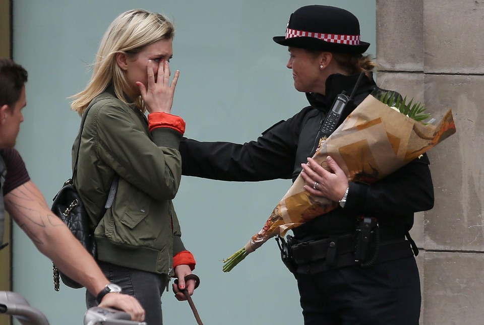 A police officer comforts an emotional woman at the scene of the attack on Sunday