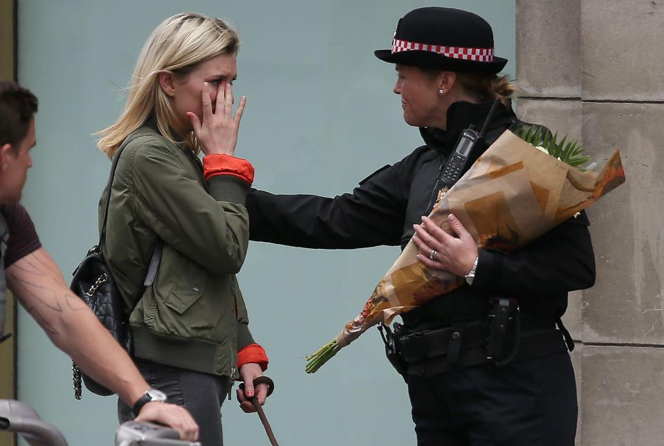  A police officer comforts an emotional woman at the scene of the attack on Sunday