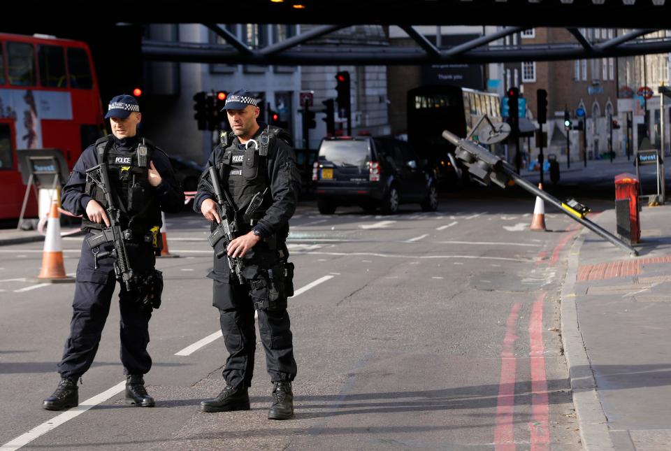  Armed cops stand at the scene of the cordon today where a traffic light can be seen almost completely keeled over