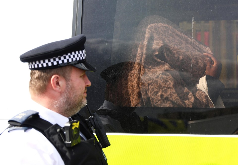 The detained individual sits inside a police vehicle after the raid