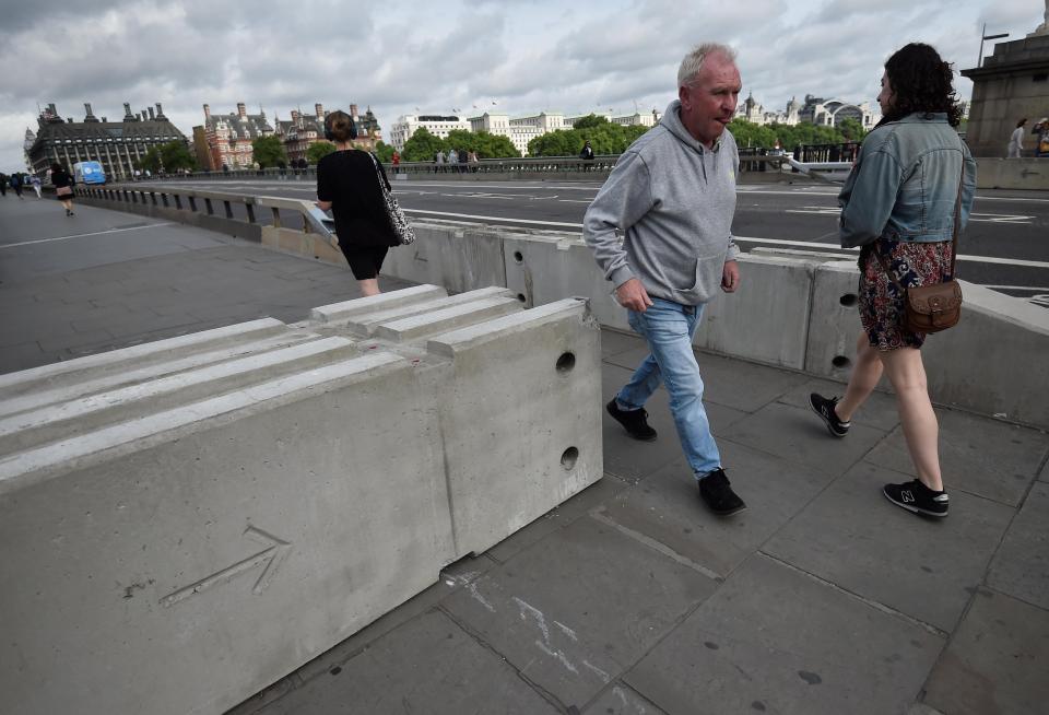  A man walks through the gap in the concrete blocks which have been erected at the end of Westminster Bridge