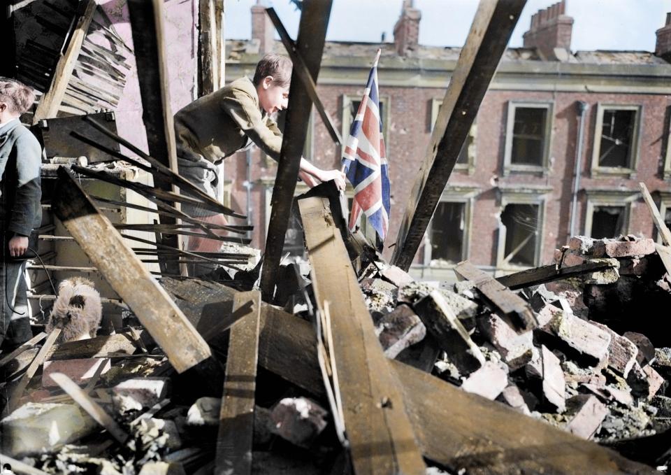  1940: A young boy, called Leslie, plants a Union flag among the rubble and debris after an air raid destroys his London home