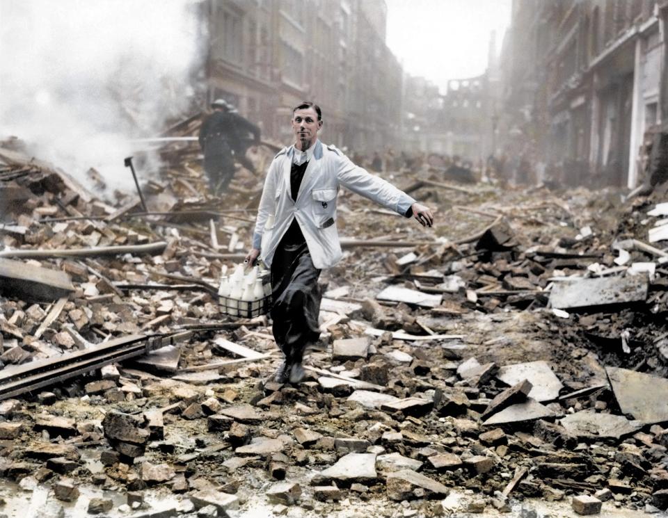  A milkman continues to do his morning round after a London street is devastated by German bombing. Fireman work to dampen down the ruins behind him.