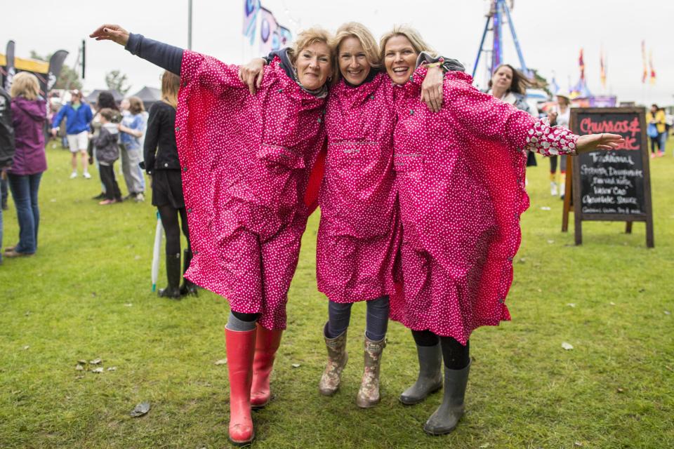  A group of friends don matching fuschia ponchos to ward of the showers