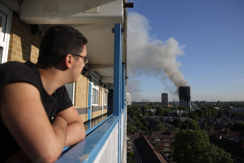 A resident from another building watches smoke billow into the sky as the sun rose over London