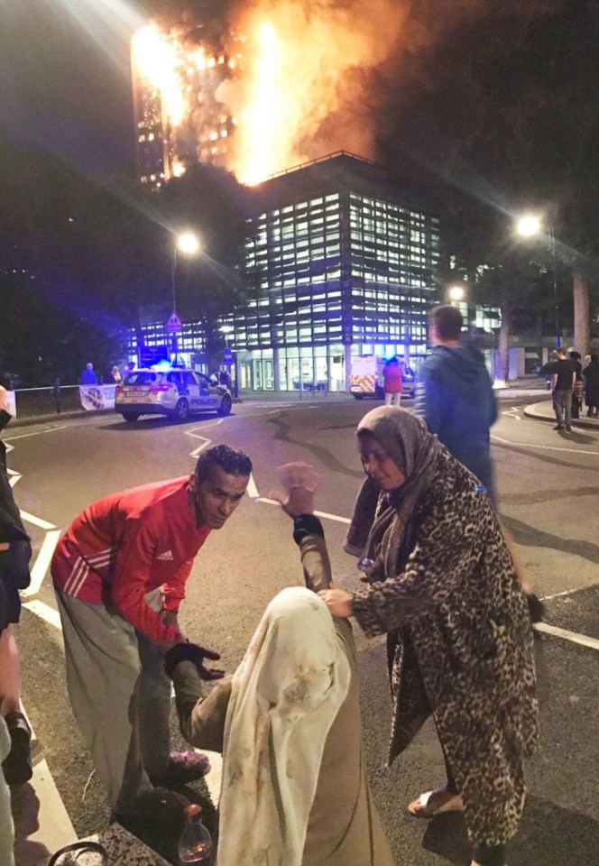 A distraught woman falls to her knees as she watches the tower go up in flames, as others comfort her