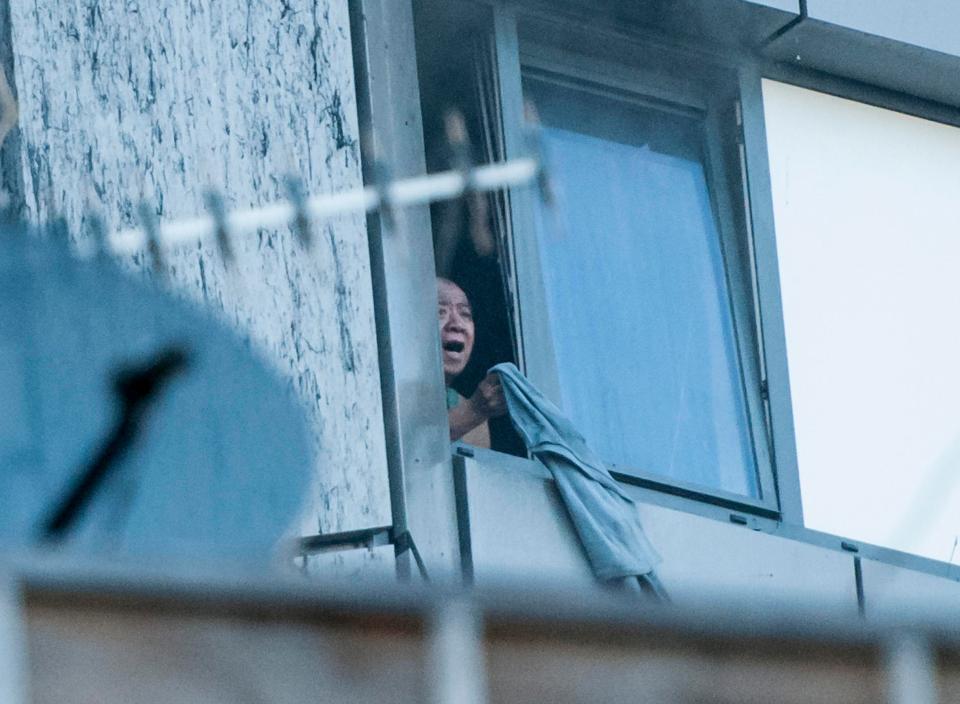  A trapped resident waves from his window as fire rages throughout the tower block