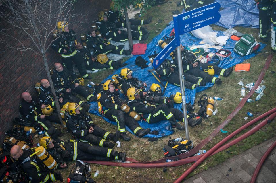  Exhausted firefighters rest at the scene of the inferno