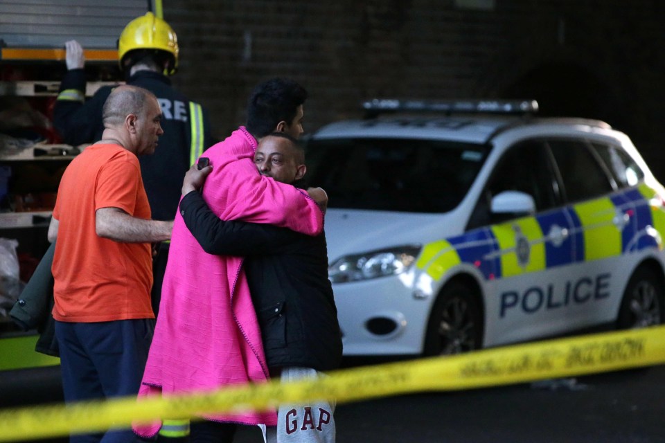 Two men hug within the security cordon following the fire 