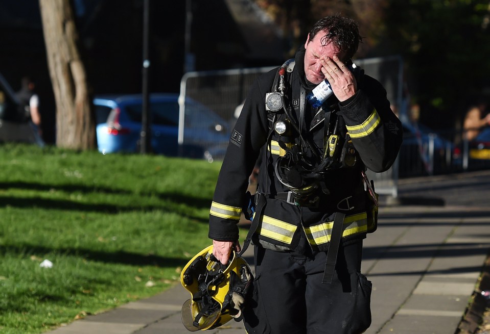 A fireman was seen looking tired and upset at the scene in west London this morning 