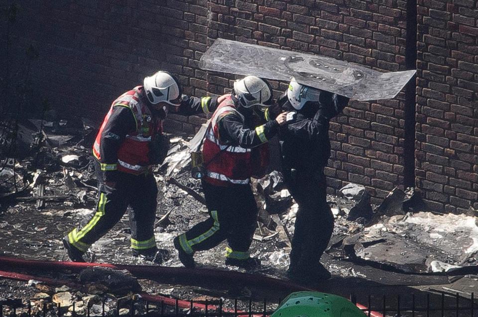  Police officers with riot shields escort firefights underneath shields to protect themselves from falling debris as they enter the tower block