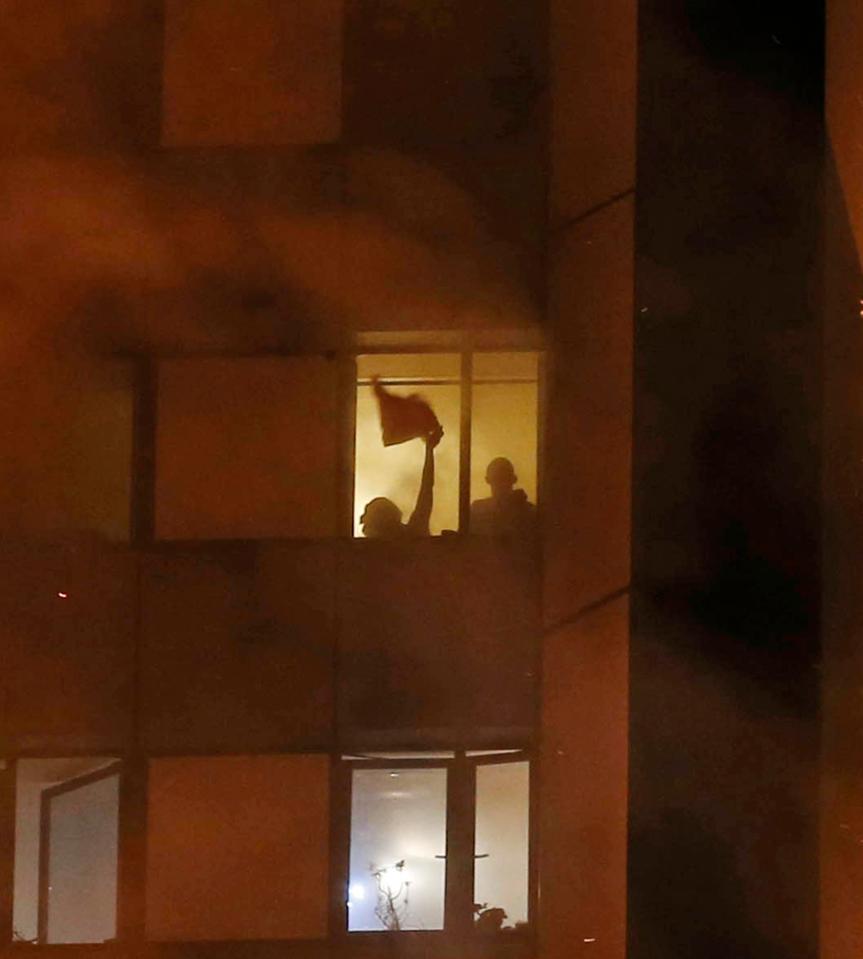  People wave for assistance through the billowing smoke