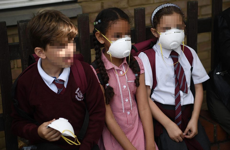  Young children close to the tower block wear face masks as smoke continues to billow from the burning building