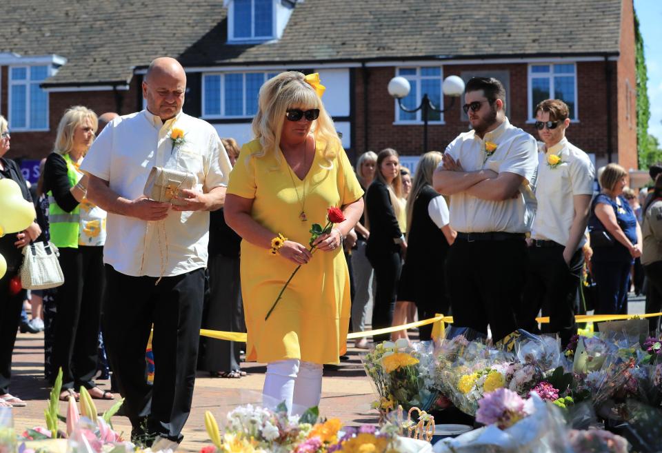  Georgina's mum Lesley lays a rose for her daughter surrounded by the teen's dad Simon and brothers Daniel and Harry