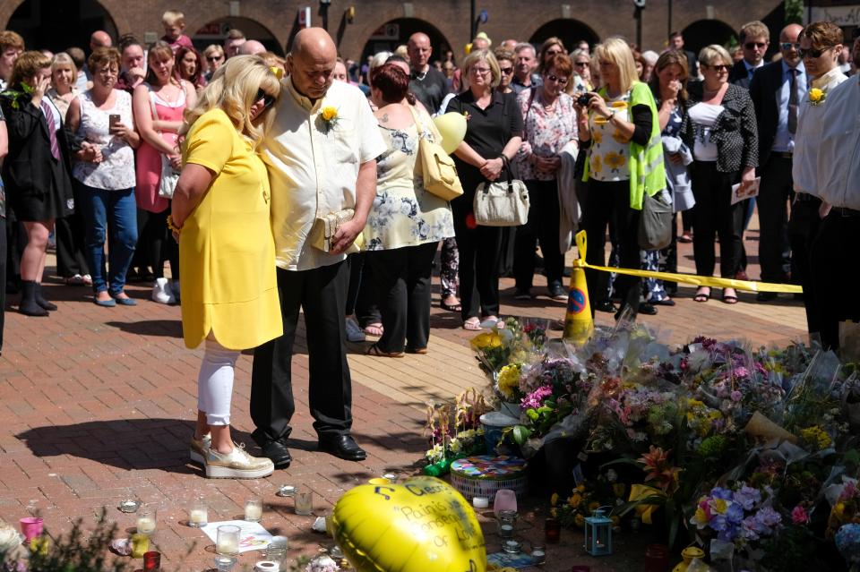  The teen's parents look at flowers left in Tarleton, Lancs, by well-wishers