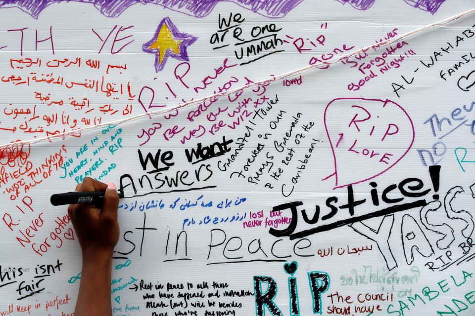  A woman writes on a message wall near the scene of the fire which destroyed the Grenfell Tower block