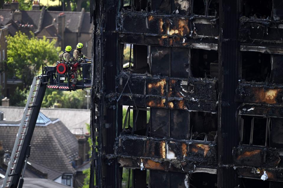  Firemen perched on a ladder investigate the burned out tower block