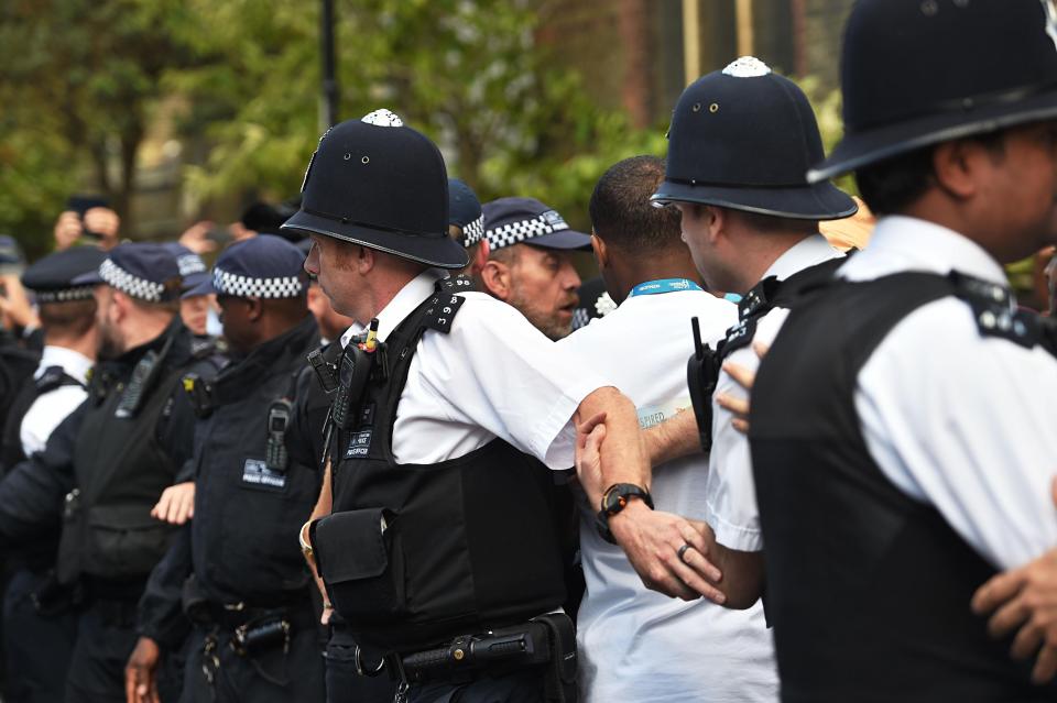  Police officers hold back angry protestors outside the church where Theresa May was visiting victims of the disaster