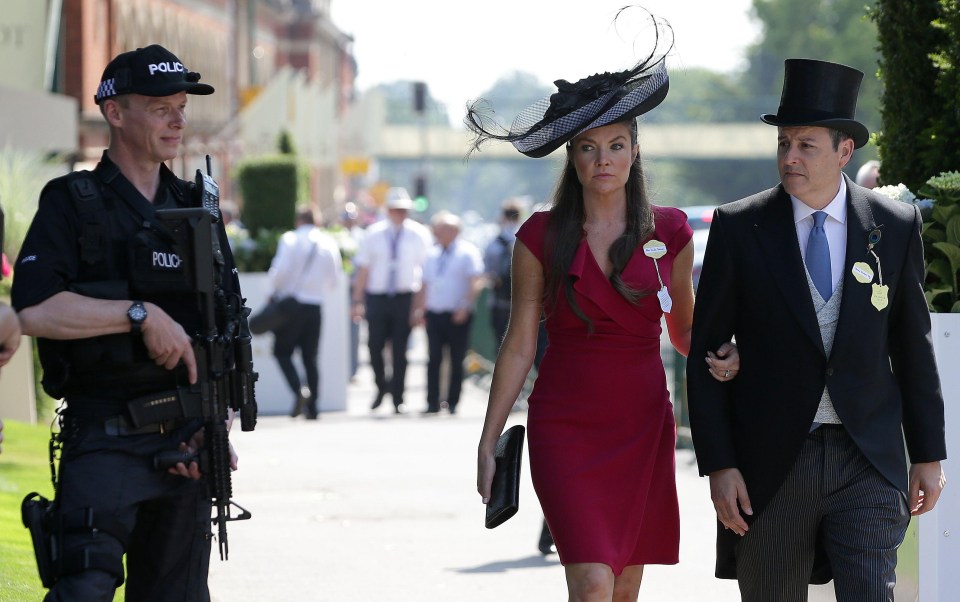 A gun cup stands guard as a smartly-dressed couple enjoys the first day of this year’s Ascot festival