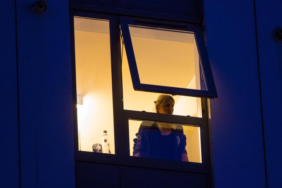  A resident of Burnham Tower peers out of the window of her apartment as the evacuation is carried out