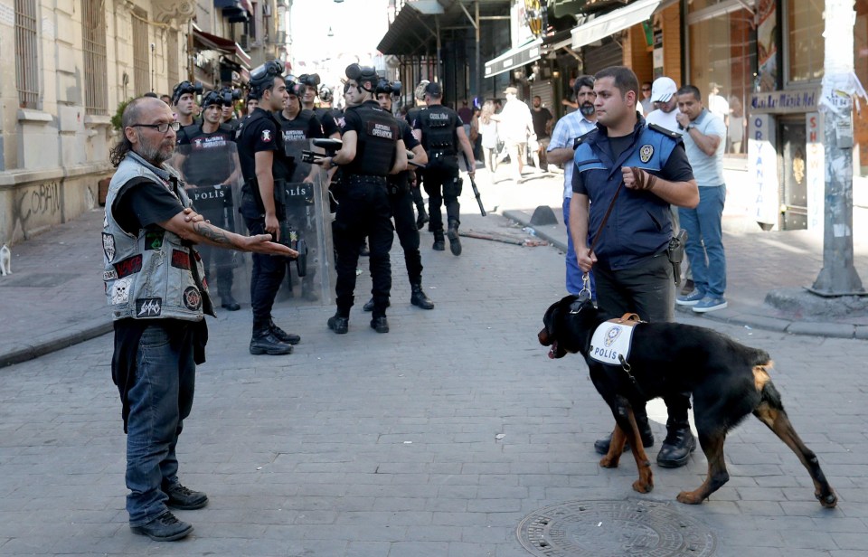 A man angrily gestures at a police officer with a dog in Istanbul