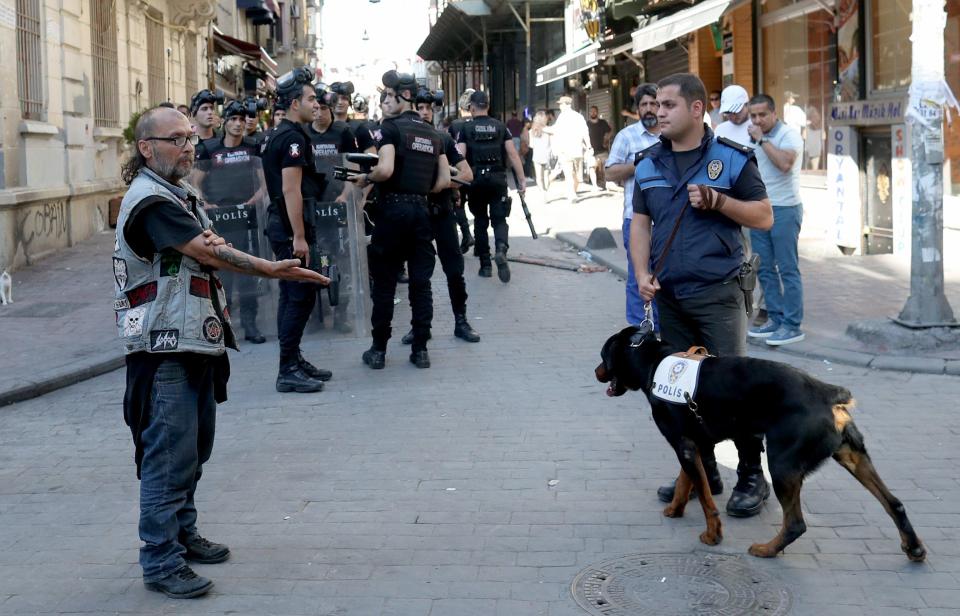  A man angrily gestures at a police officer with a dog in Istanbul