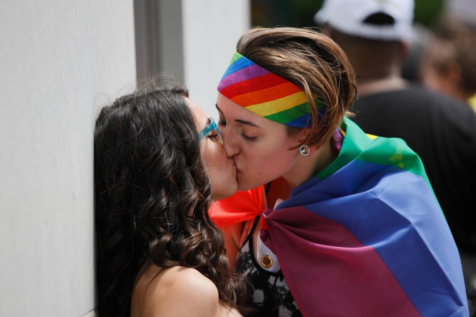 Marchers wearing rainbow flags share a kiss 