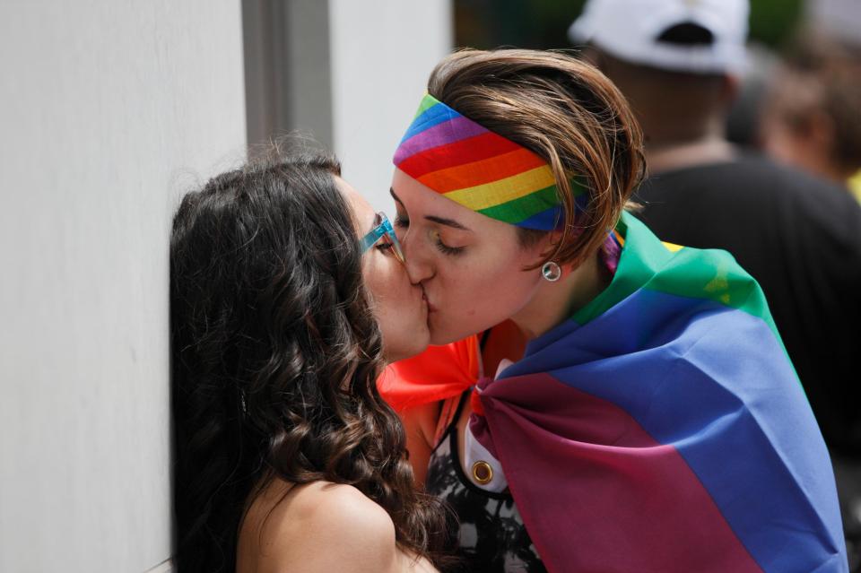  Marchers wearing rainbow flags share a kiss