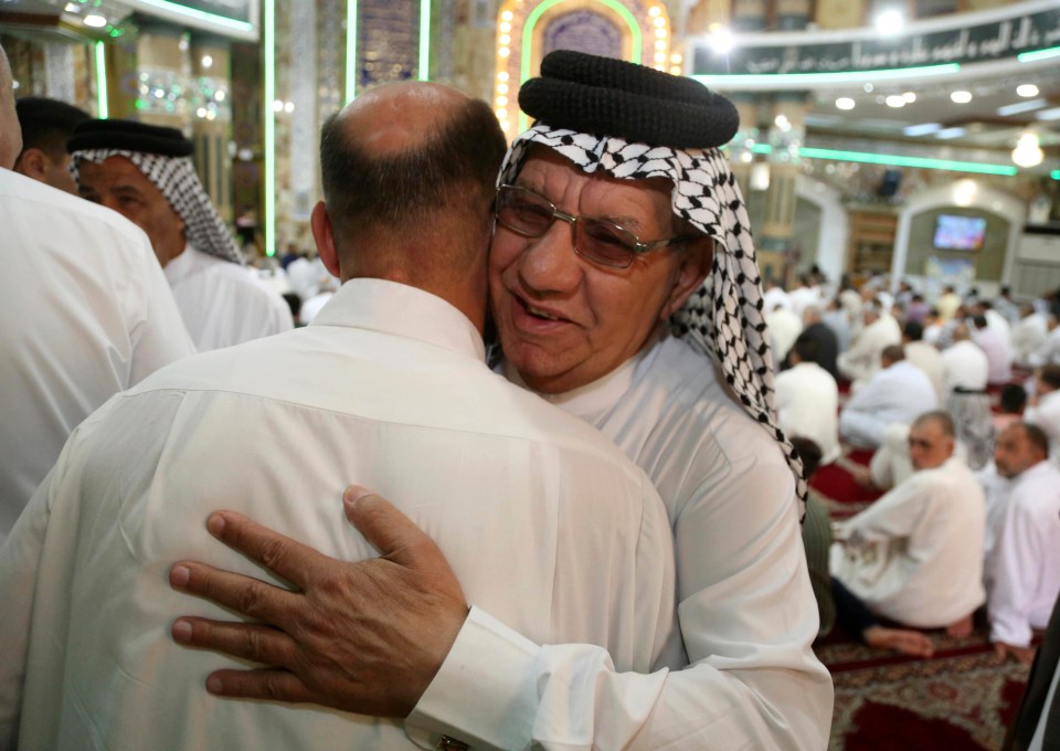 Two men hug in Baghdad, Iraq, on the first day of Eid al-Fitr