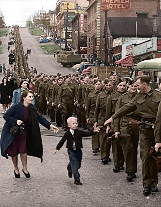  1940: Claude P. Detloff first snapped this photo of the British Columbia Regiment as they made their way down Columbia Street intersection, Canada. In this moment, a young boy named Warren ran from his mum to reach out his hand to his dad, Private Jack Bernard