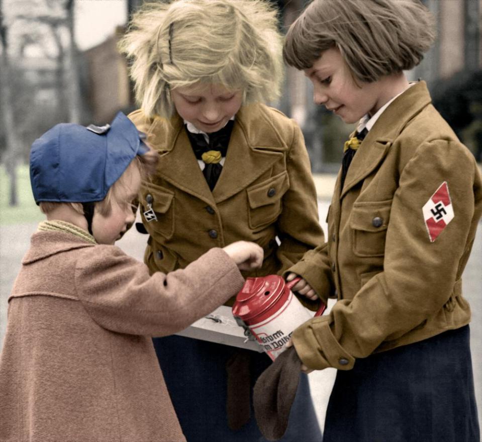  Two Nazi girls collect donations for the war effort. They appear to be selling WHW, or winterhilfswerke pins, as they attempt to raise funds for the poor during the depression.