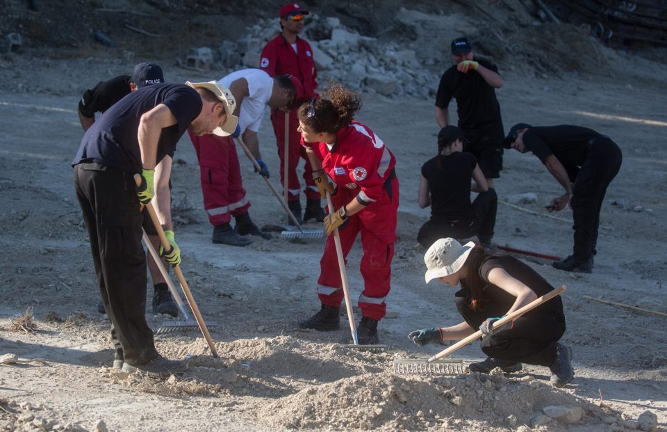  South Yorkshire Police and members of the Greek rescue service (red) sift through soil at the search site of the missing toddler last year