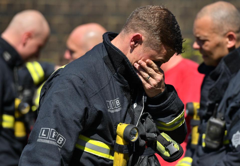  A firefighter looks at the floral tributes left by the Latymer Community Centre before a minute's silence near to Grenfell Tower in June