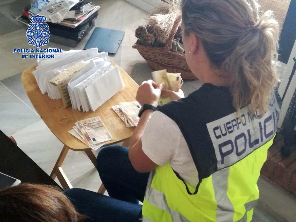  An officer counts 50 euro notes found in the raid