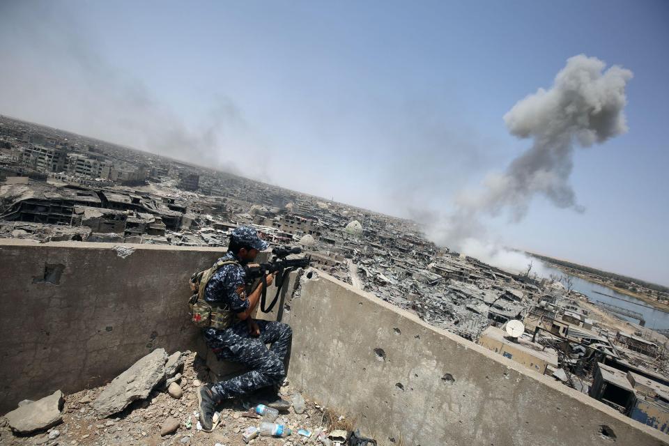  An Iraqi forces sniper looks on as smoke billows following an airstrike by coalition aircraft