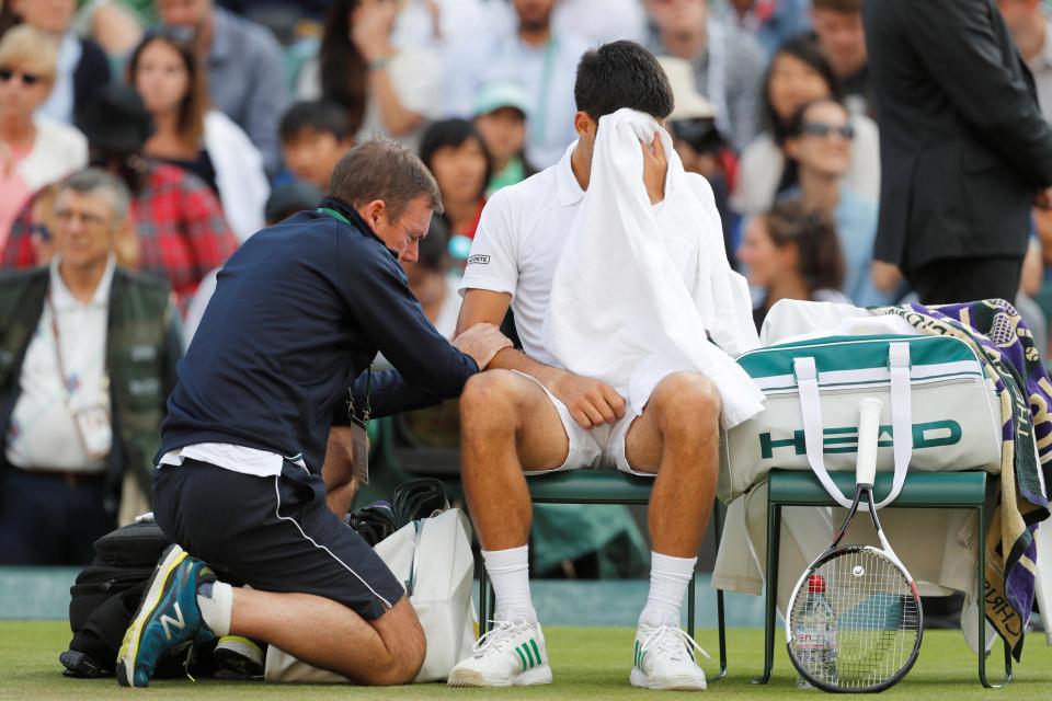 Novak Djokovic receives treatment on his elbow from a trainer