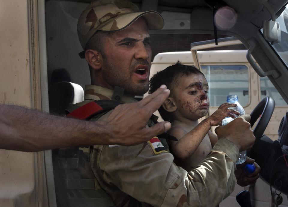  A young boy - who looks around two - grasps at a bottle of water after being rescued from certain death