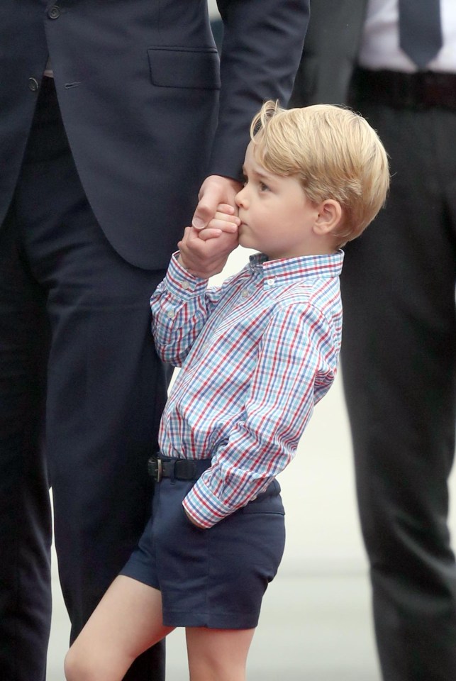  George gives his dads hand a quick kiss as they stand together on a runway red carpet