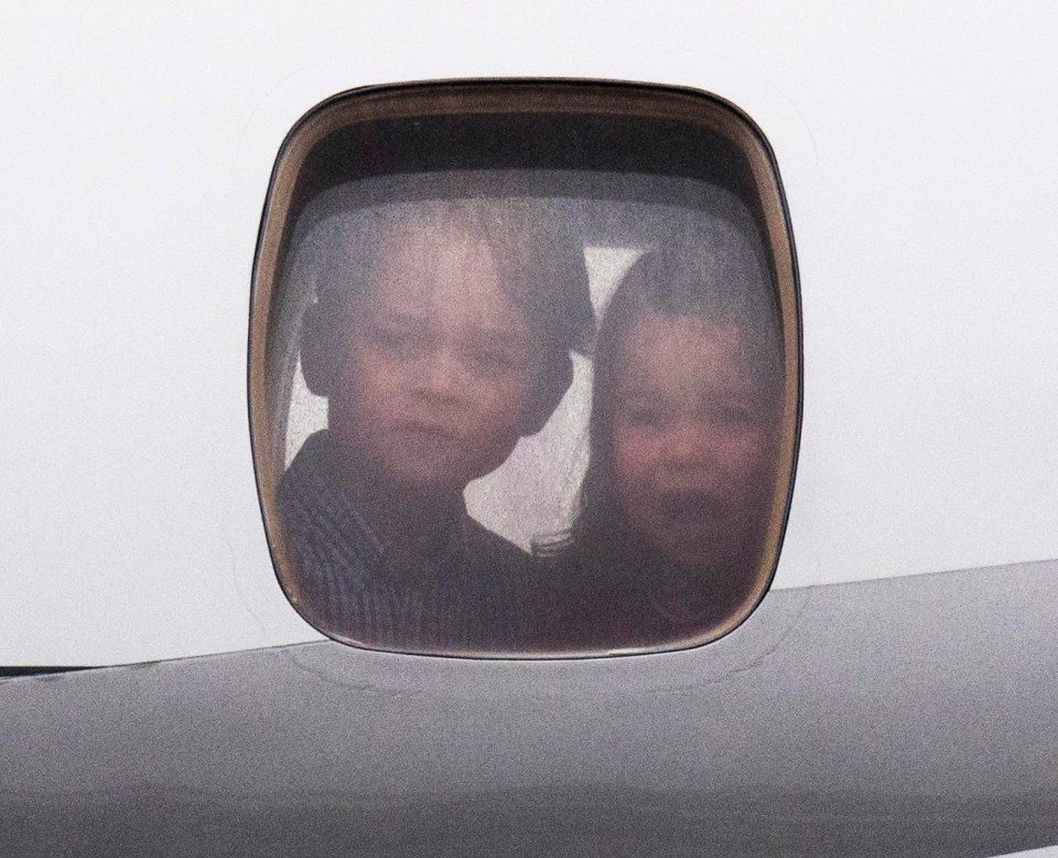 Prince George and Princess Charlotte make faces from inside the plane