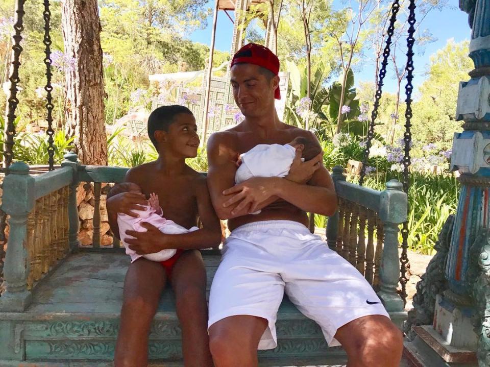  Proud dad Cristiano Ronaldo cradles one of his newborn twins as son Cristiano Jr holds the other